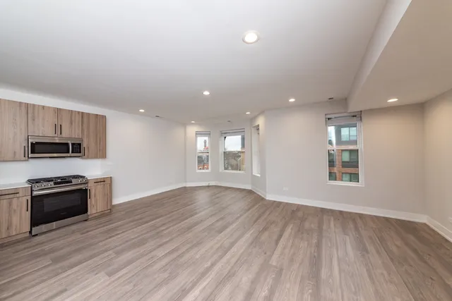 an empty room with wooden floor and stainless steel appliances