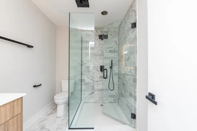 a bathroom with a granite countertop shower a toilet and a shower