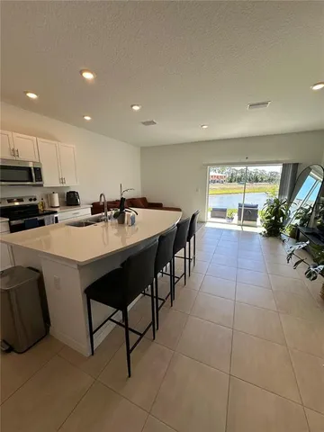 a kitchen with sink a refrigerator and chairs
