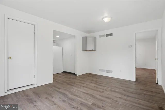 a view of an empty room with wooden floor and closet