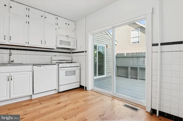 a kitchen with granite countertop white cabinets and white appliances