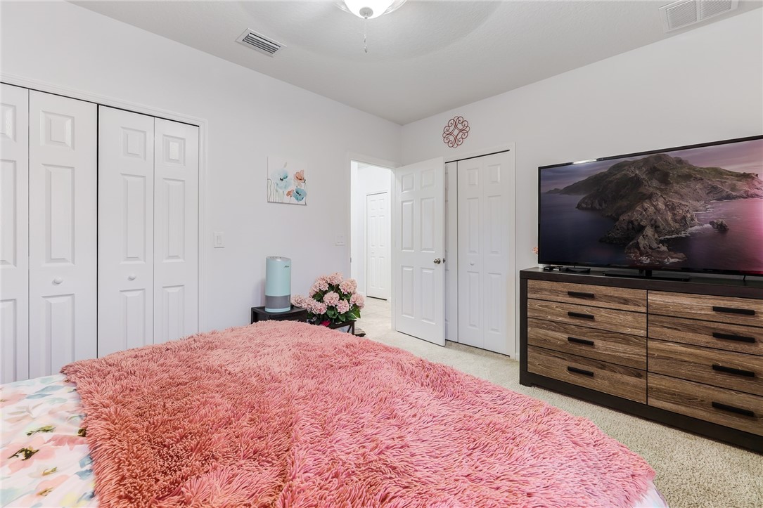 5997 Ridge Lake Circle Vero Beach, FL 32967 - Photo 26 of 36 a bedroom with a bed and a flat screen tv in it