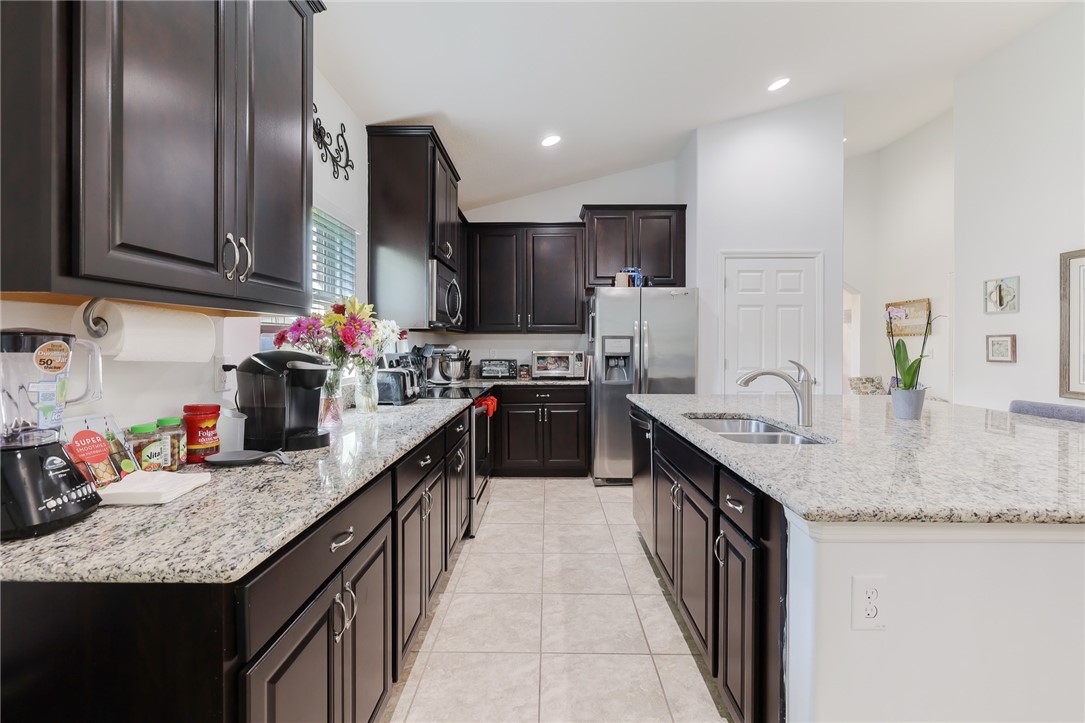 5997 Ridge Lake Circle Vero Beach, FL 32967 - Photo 8 of 36 a kitchen with granite countertop stainless steel appliances a sink dishwasher a refrigerator oven and white cabinets next to a window