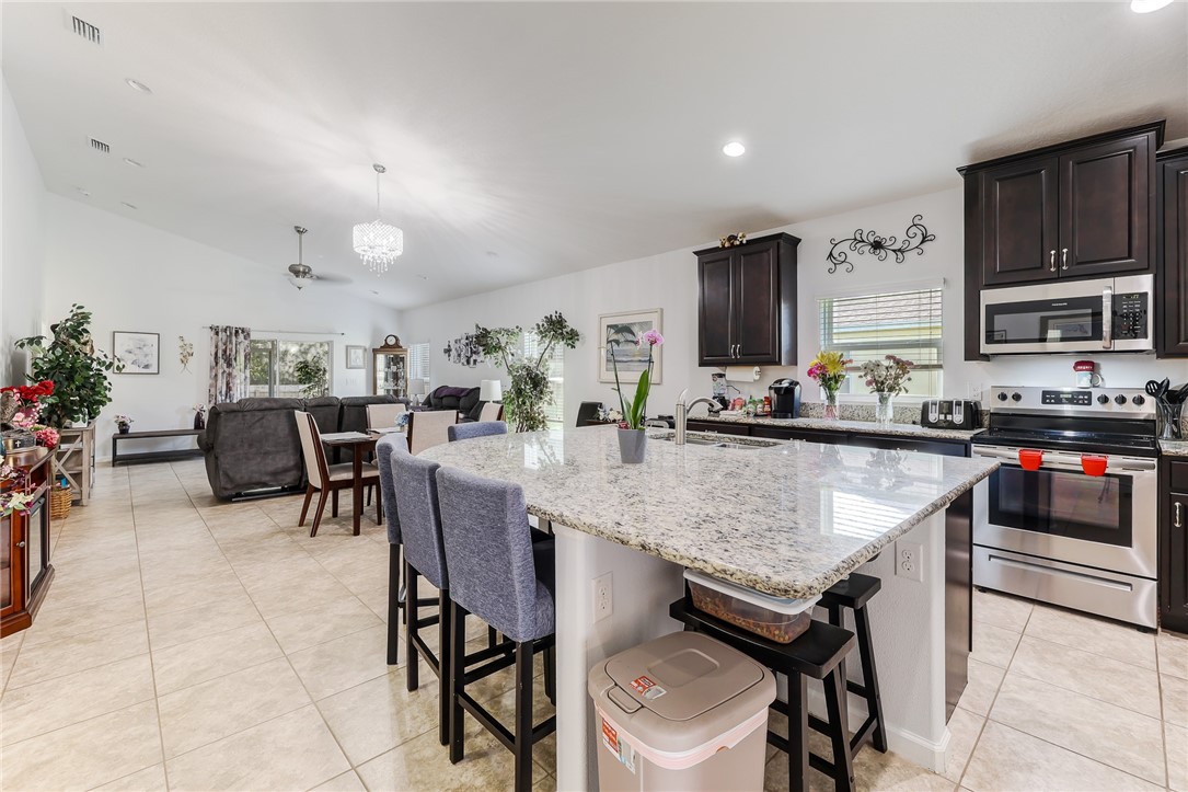 5997 Ridge Lake Circle Vero Beach, FL 32967 - Photo 10 of 36 a kitchen with granite countertop a table chairs stove and cabinets