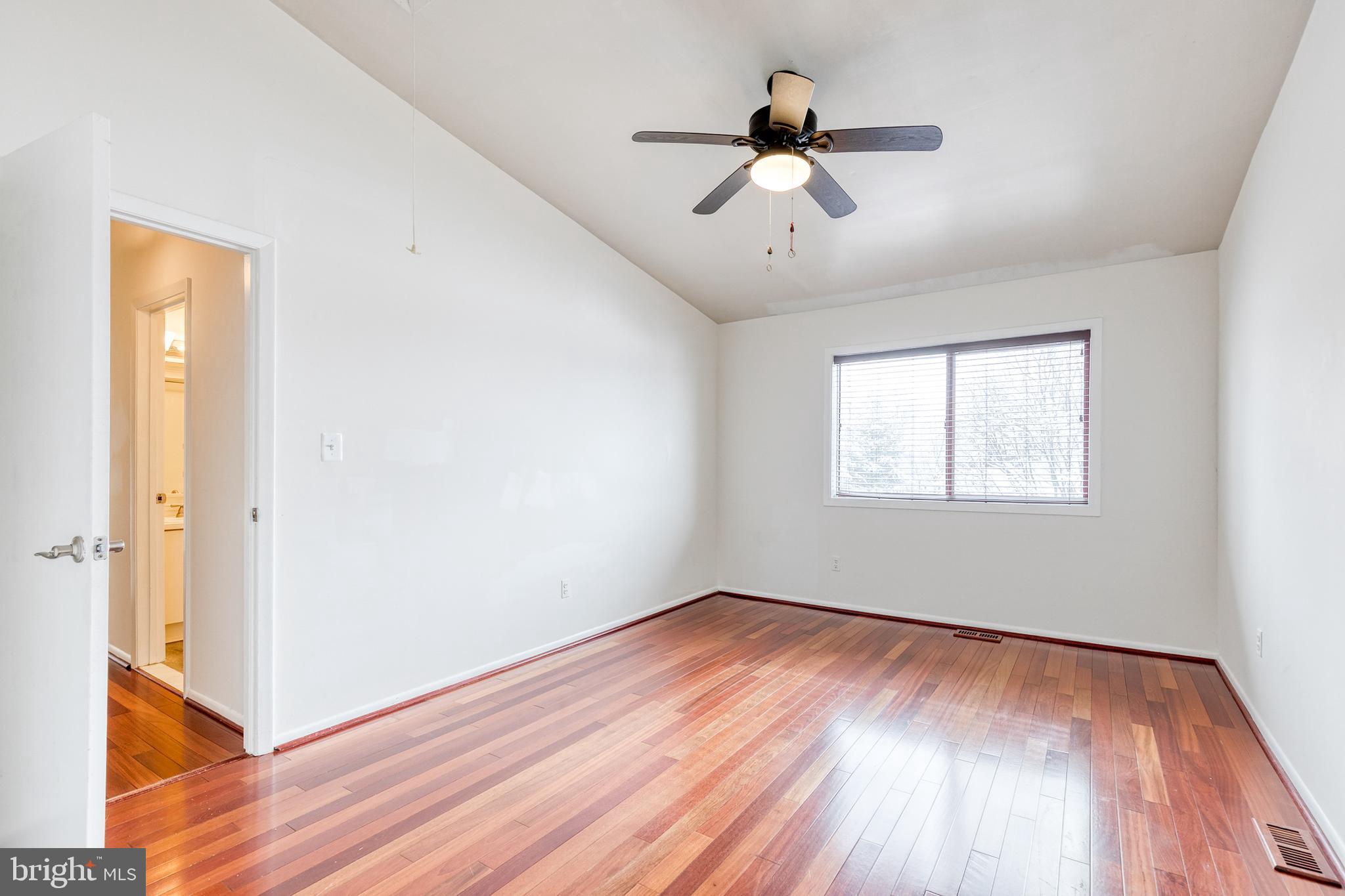 8008 Valley Manor Road, Unit 3B Owings Mills, MD 21117 - Photo 16 of 19 a view of a room with wooden floor a ceiling fan and windows