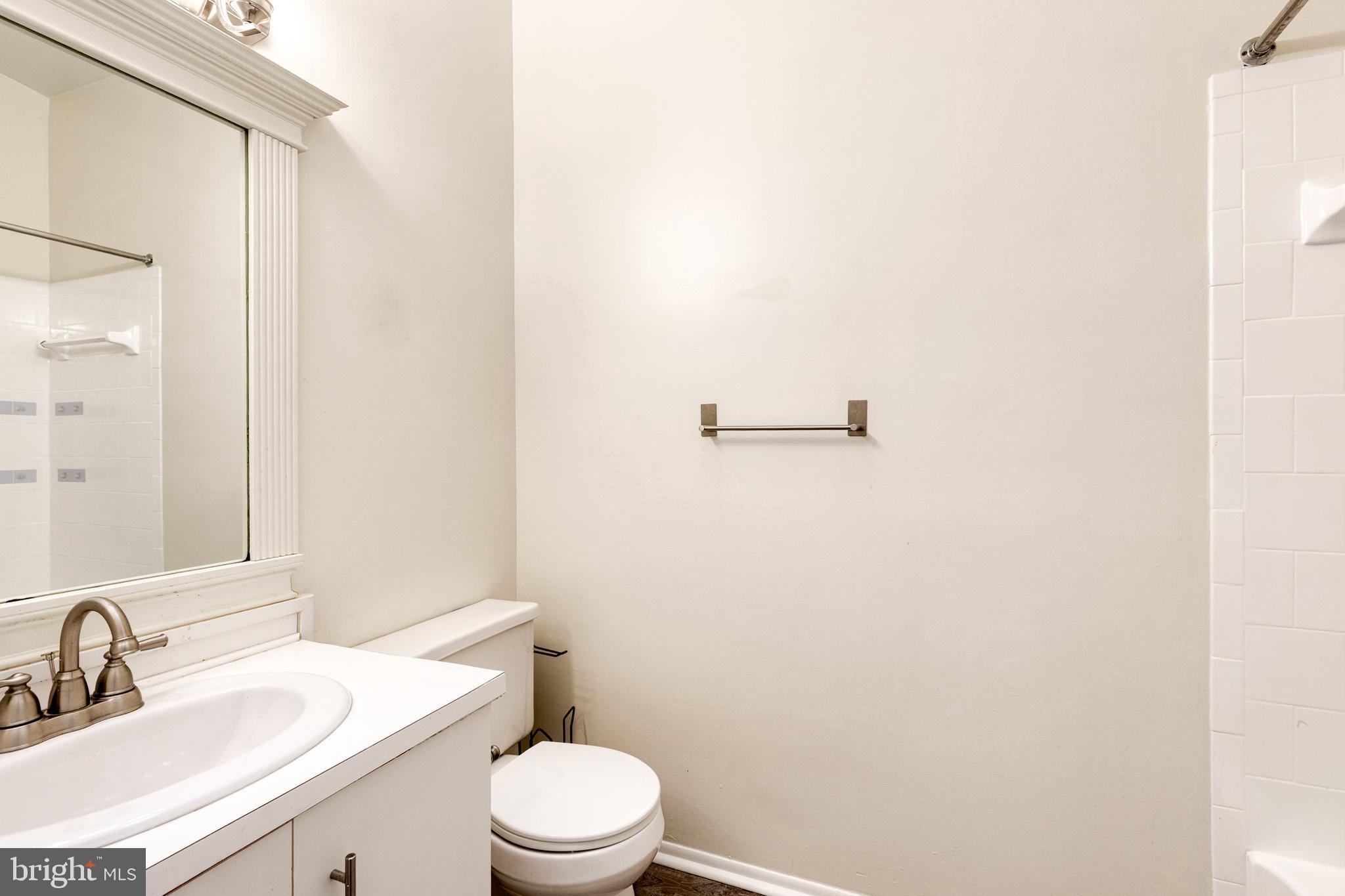 8008 Valley Manor Road, Unit 3B Owings Mills, MD 21117 - Photo 18 of 19 a bathroom with a white toilet sitting next to a sink and a mirror