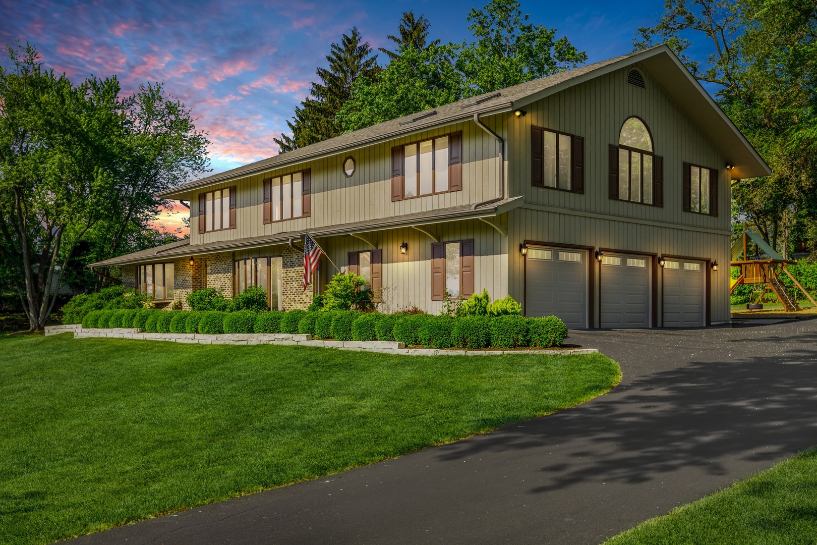 a front view of a house with a yard and green space