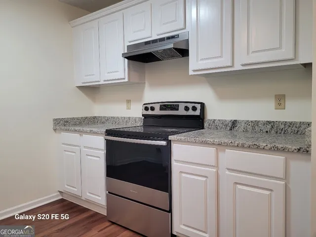 a kitchen with granite countertop white cabinets and white appliances