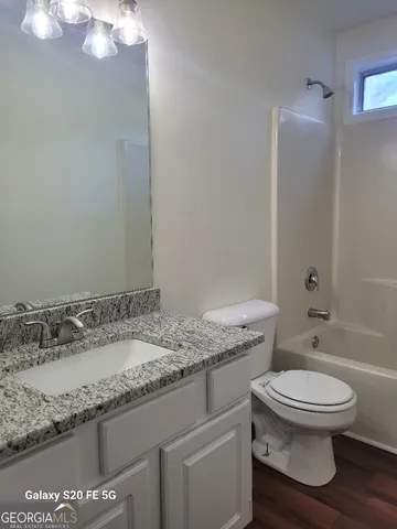 a bathroom with a granite countertop sink a toilet and a mirror