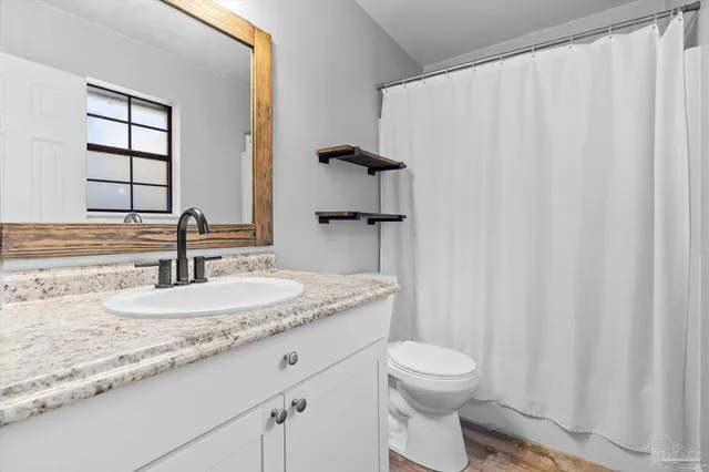 a bathroom with a granite countertop sink toilet and a mirror
