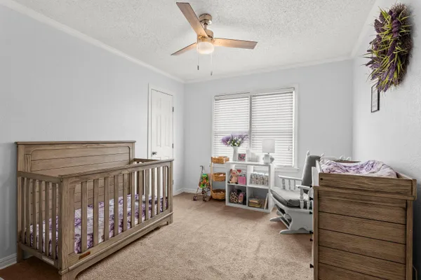 a bedroom with a baby bed a desk and chair with the bedroom
