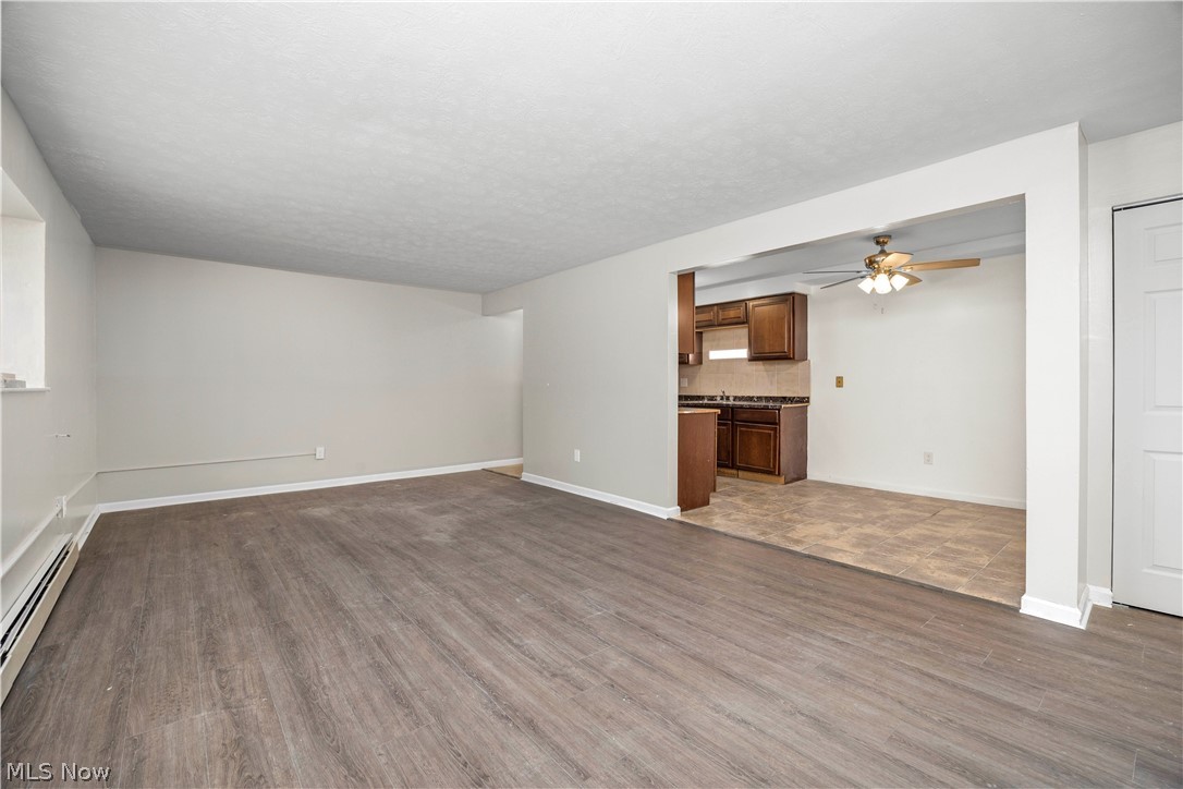 5382 Lee Road, Unit 102 Maple Heights, OH 44137 - Photo 7 of 25 Unfurnished living room with ceiling fan, dark wood-type flooring, and baseboard heating