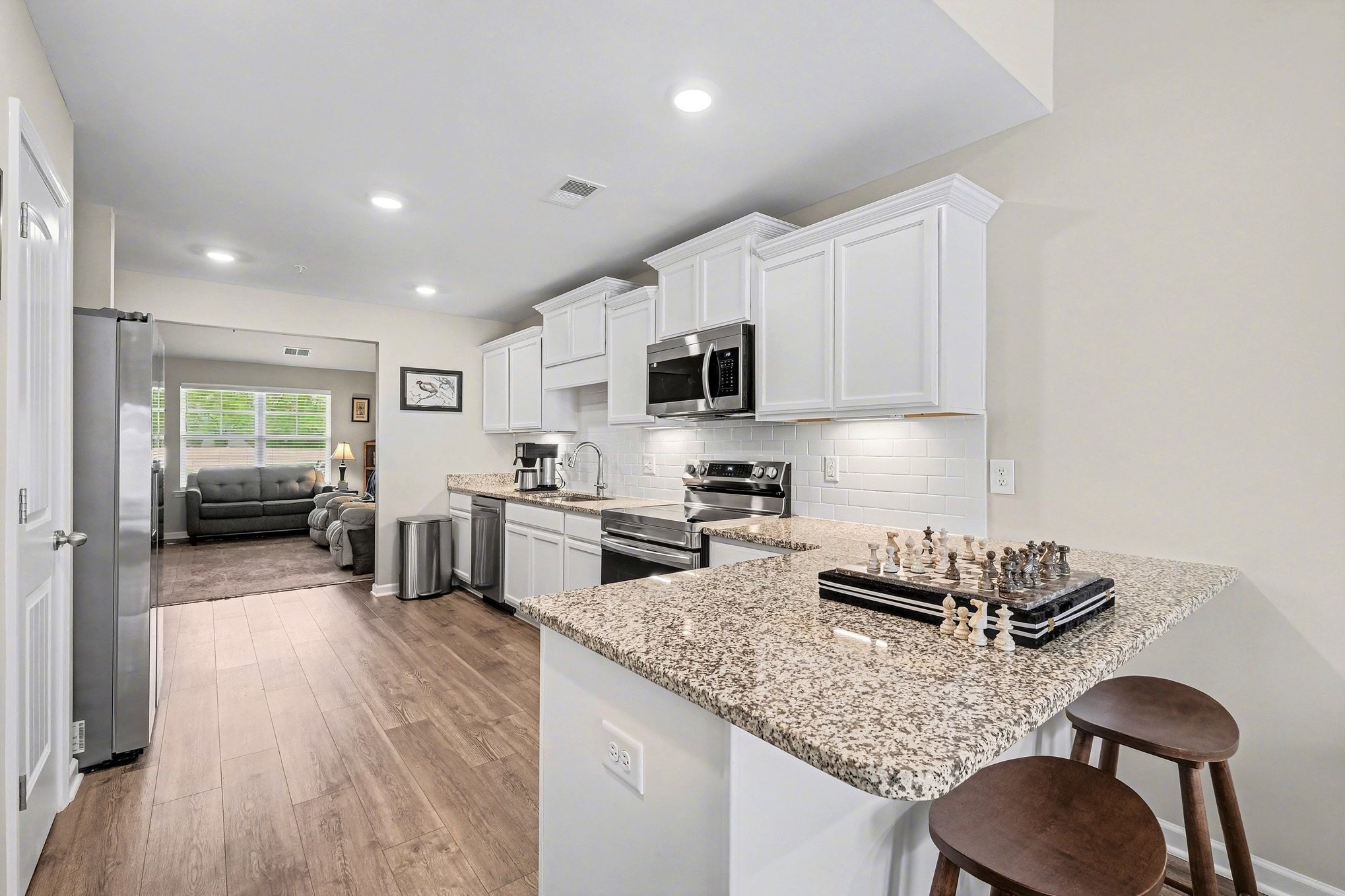 381 Ezra Street Pleasant View, TN 37146 - Photo 11 of 31 a kitchen with stainless steel appliances granite countertop a sink dishwasher a stove top oven a dining table and chairs with wooden floor