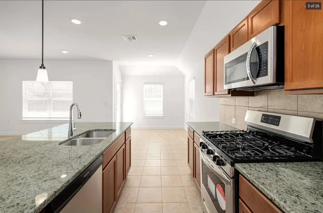 a kitchen that has a sink wooden cabinets and a stove top oven with granite countertops