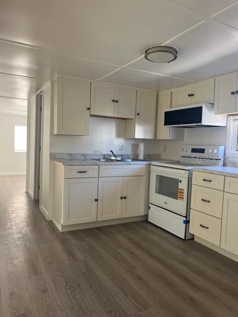 10315 Cortez Road West, Unit 1B Bradenton, FL 34210 - Photo 8 of 48 a kitchen with white cabinets stainless steel appliances and wooden floor