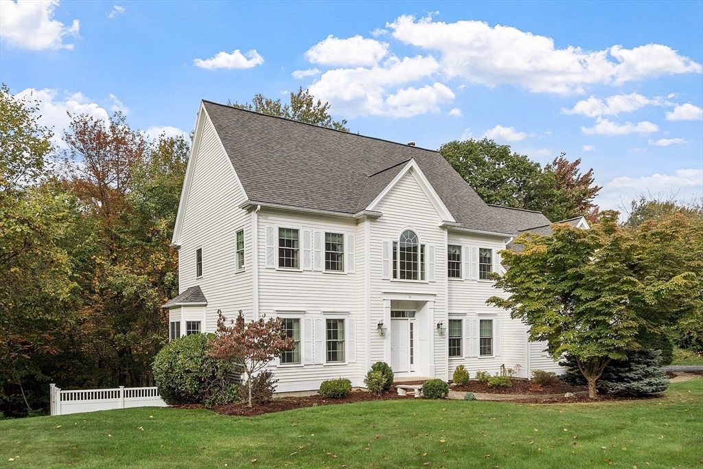 a view of a white house next to a yard with big trees