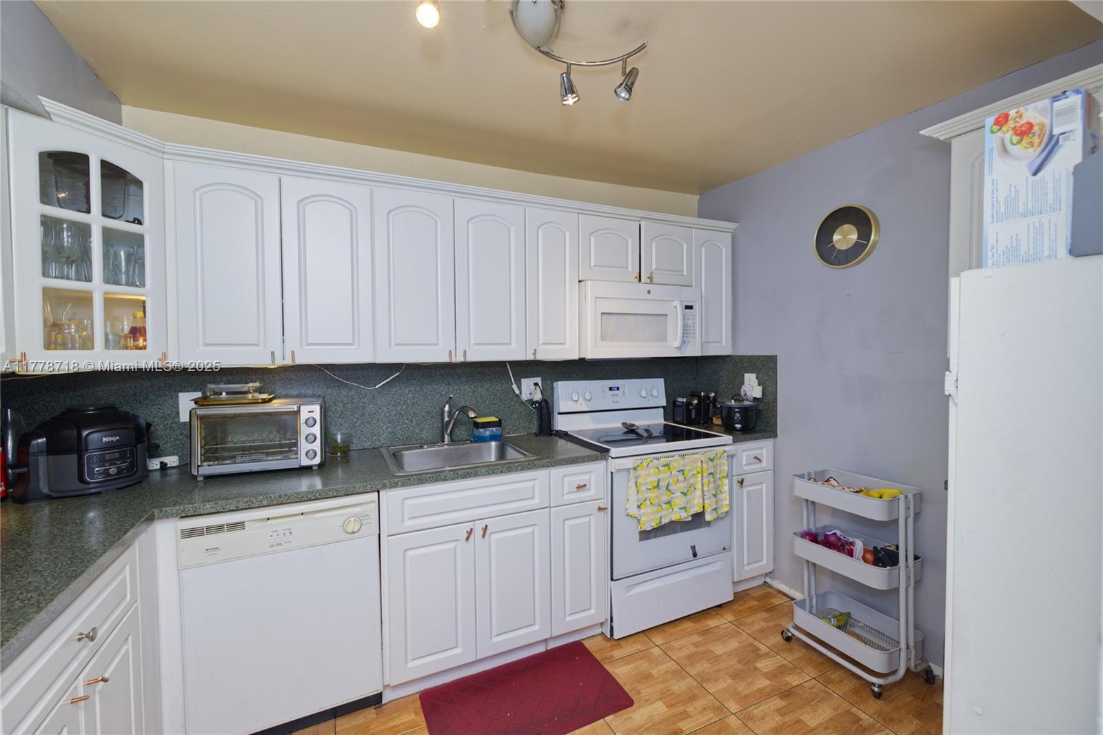 3195 Foxcroft Road, Unit F302 Miramar, FL 33025 - Photo 11 of 28 a kitchen with a refrigerator a stove and a cabinets