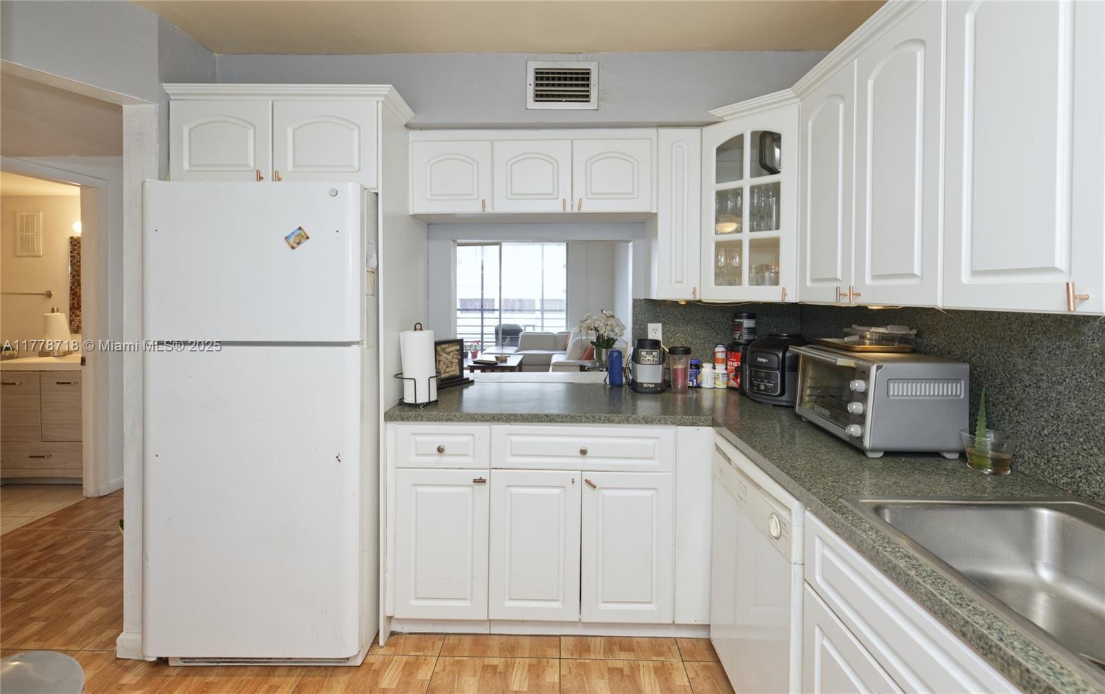 3195 Foxcroft Road, Unit F302 Miramar, FL 33025 - Photo 3 of 28 a kitchen with white cabinets and refrigerator