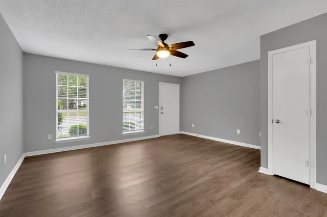 a view of an empty room with wooden floor and a window
