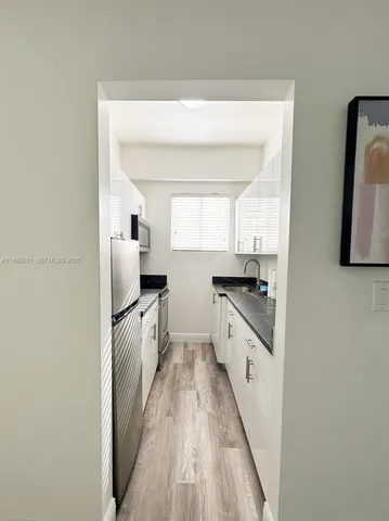 a kitchen with stainless steel appliances a refrigerator sink and white cabinets