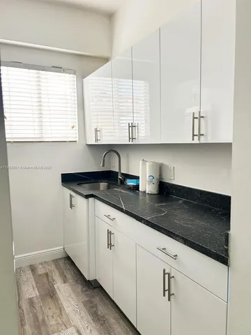 a kitchen with granite countertop white cabinets and a sink