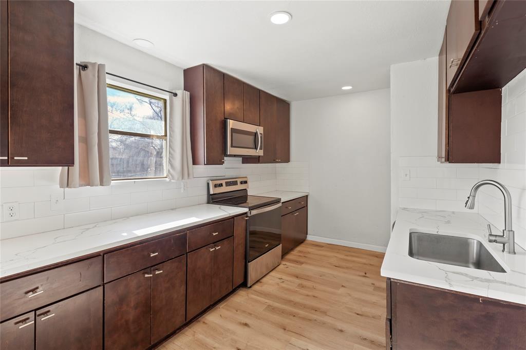 1012 East Dallas Street Mansfield, TX 76063 - Photo 10 of 25 a kitchen with stainless steel appliances granite countertop a sink stove and microwave
