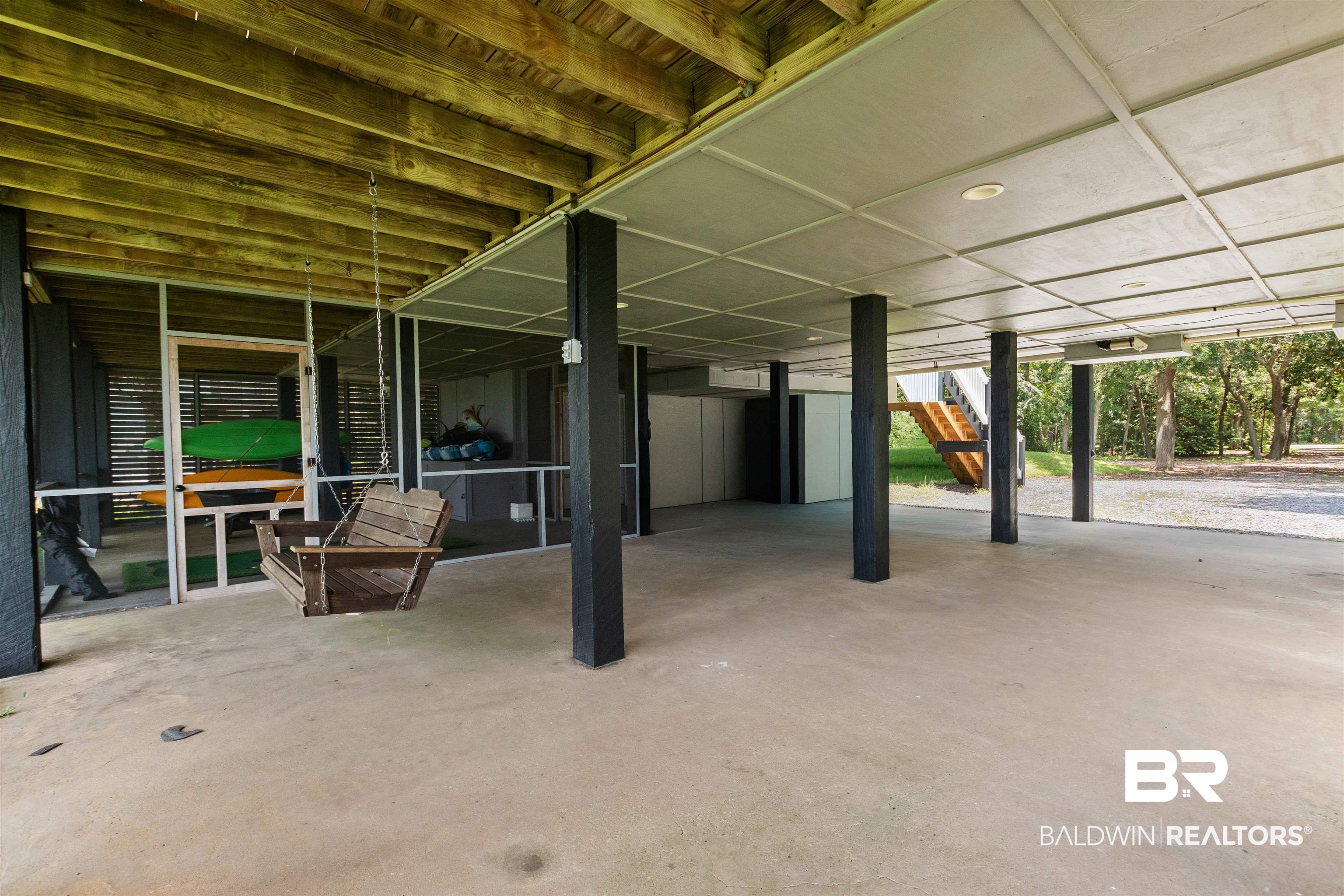 9581 South Bay Street Foley, AL 36535 - Photo 26 of 44 Expansive concrete pad beneath the structure, featuring a screened-in porch area with a wood-plank swing