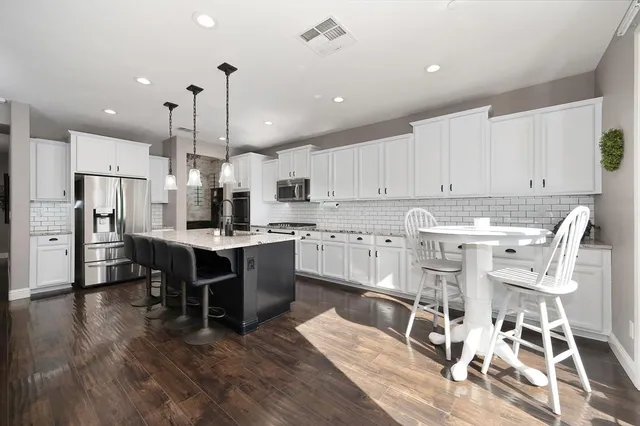 a kitchen with stainless steel appliances kitchen island granite countertop a table chairs sink and cabinets