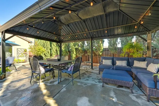 a view of a patio with table and chairs under an umbrella with a small yard