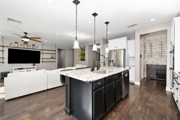 a living room with stainless steel appliances kitchen island furniture and a wooden floor