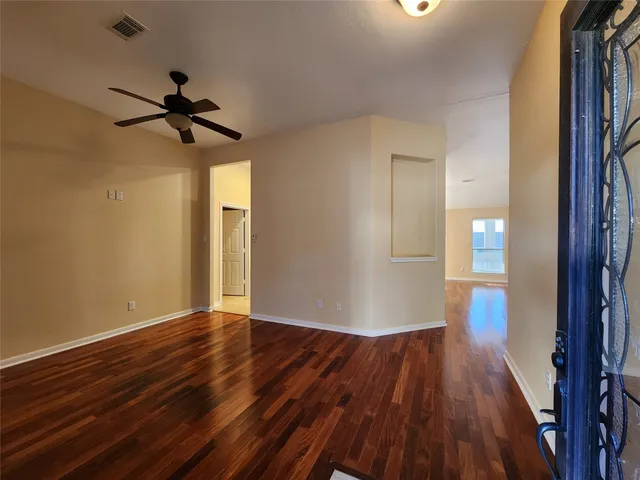 a view of empty room with wooden floor and fan