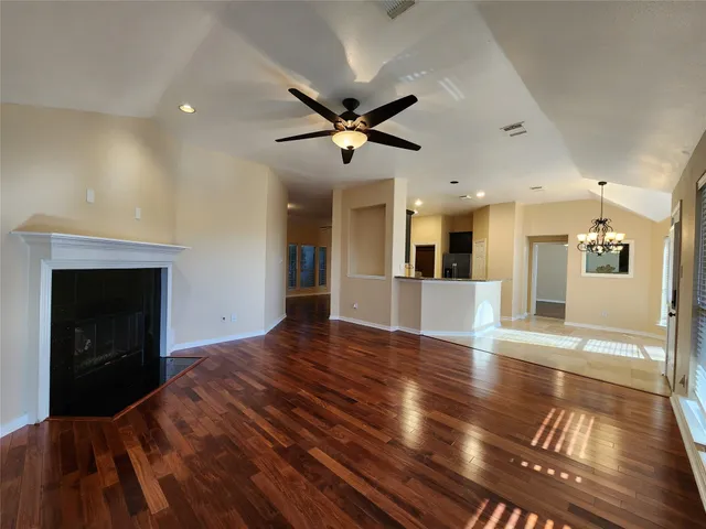 a view of a livingroom with a fireplace a ceiling fan and wooden floor