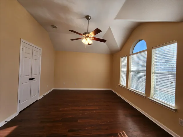 a view of an empty room with a window and wooden floor