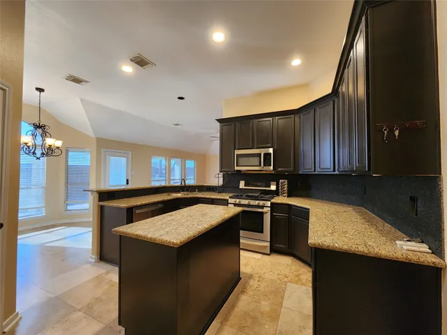 a kitchen with stainless steel appliances granite countertop a stove a sink and a refrigerator