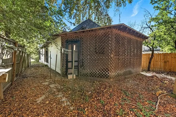 a view of a brick house with a small yard plants and a large tree
