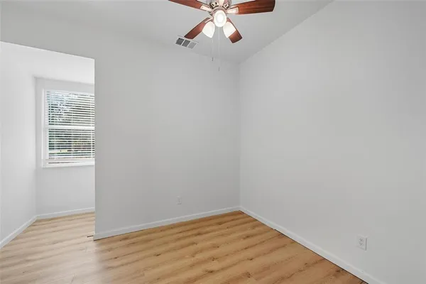 a view of an empty room with wooden floor and a window