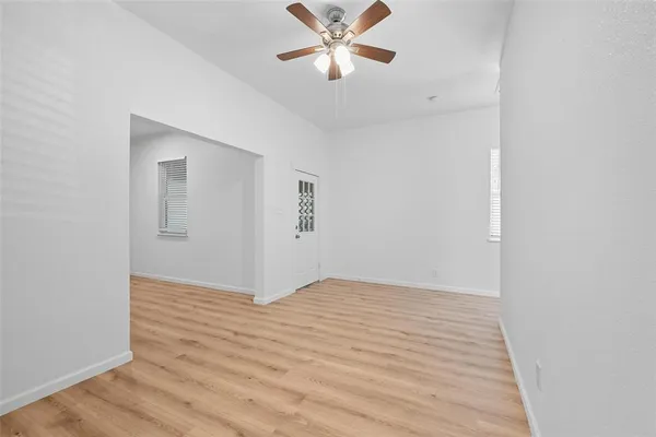 a view of an empty room with window and wooden floor