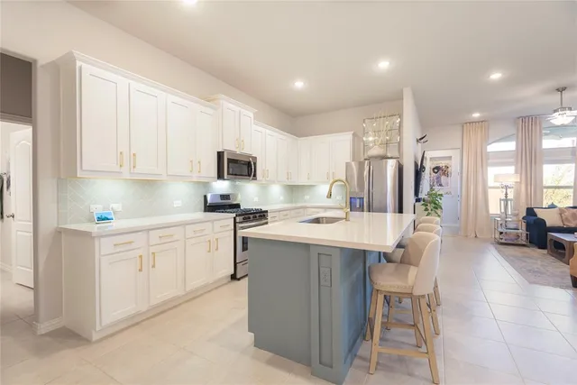 a kitchen with a sink a refrigerator and chairs