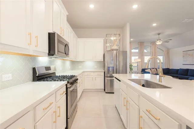 a large white kitchen with sink and washing machine