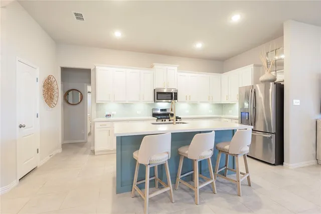 a large white kitchen with sink and washing machine