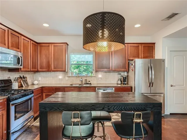 a kitchen with stainless steel appliances granite countertop a stove a sink a refrigerator and a microwave