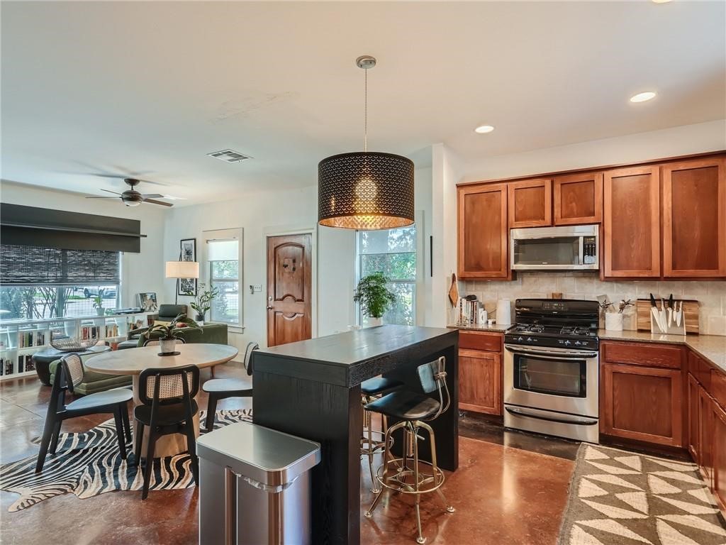 3304 East 5th Street, Unit A Austin, TX 78702 - Photo 8 of 16 a kitchen with stainless steel appliances granite countertop a stove top oven a sink a dining table and chairs with wooden floor