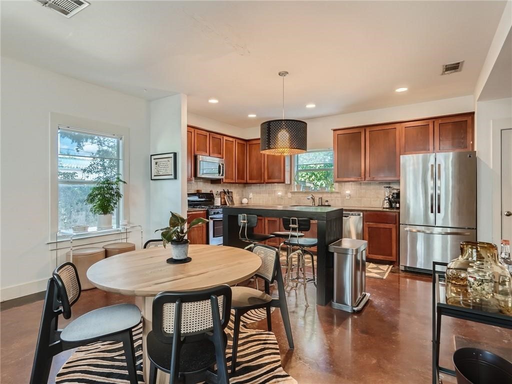 3304 East 5th Street, Unit A Austin, TX 78702 - Photo 9 of 16 a kitchen with stainless steel appliances granite countertop a stove a refrigerator a kitchen island with a dining table and chairs
