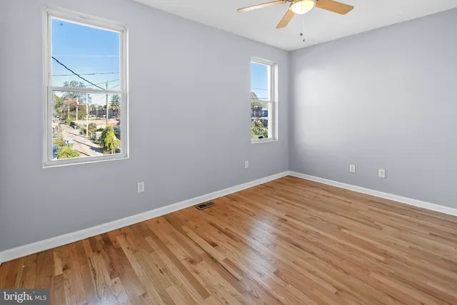 a view of empty room with wooden floor and fan