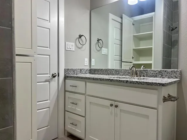 a bathroom with a granite countertop sink and a mirror