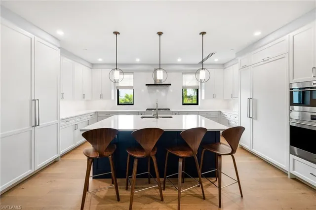 a kitchen with stainless steel appliances kitchen island granite countertop a table chairs and a refrigerator
