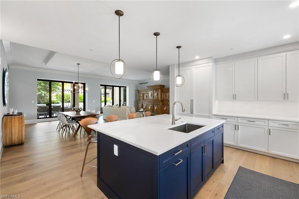 1130 3rd Avenue South, Unit 208 Naples, FL 34102 - Photo 10 of 48 a kitchen with a dining table chairs sink and wooden floor