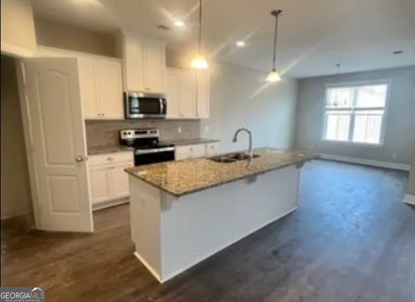 a kitchen with granite countertop a sink a counter top space cabinets and stainless steel appliances