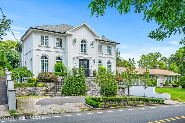 a front view of a house with a yard and potted plants