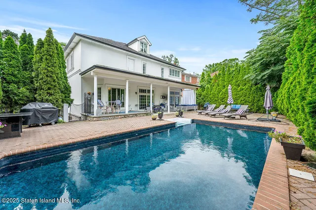 a view of a patio with couches table and chairs with plants and trees